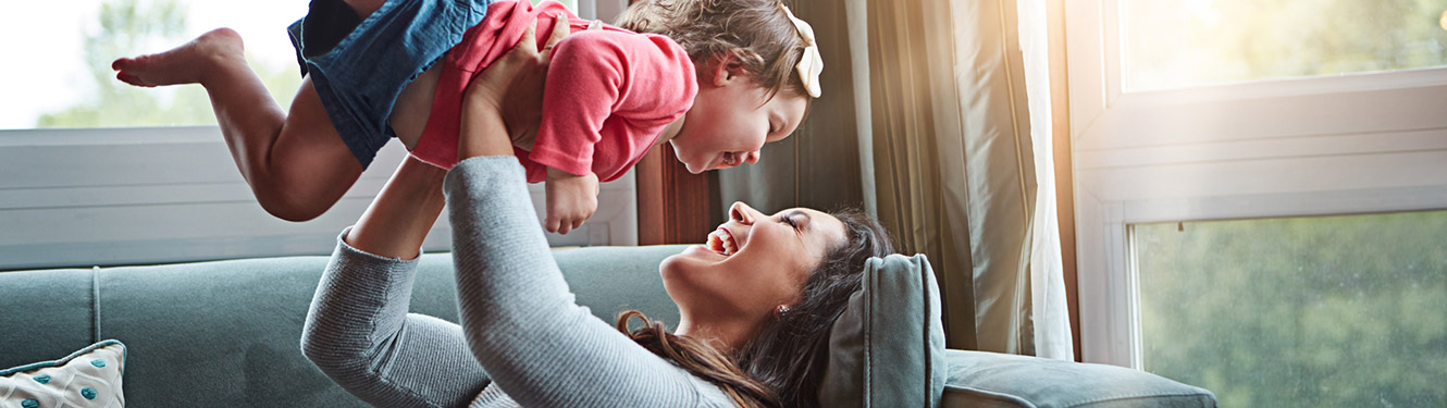 Mother and daughter playing on sofa