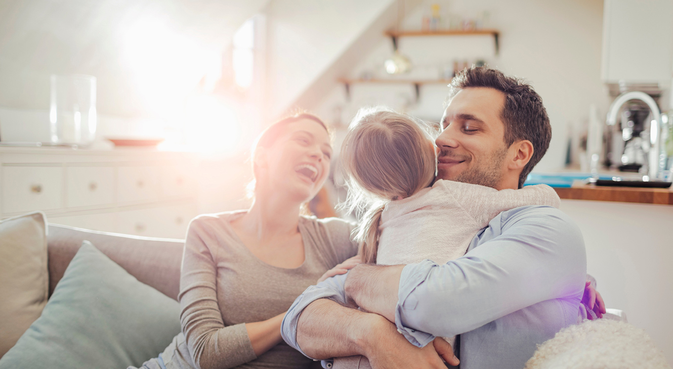Family at home hugging on sofa